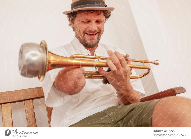 Smiling One-Armed Man Playing Trumpet at Home trumpet man one-armed musician practice home indoor cheerful smiling hat seated wooden chair brass instrument