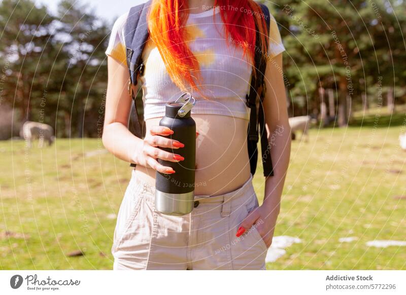 Redheaded hiker with water bottle on nature getaway redheaded woman close-up outdoor adventure trees meadow hiking female backpack trail leisure lifestyle