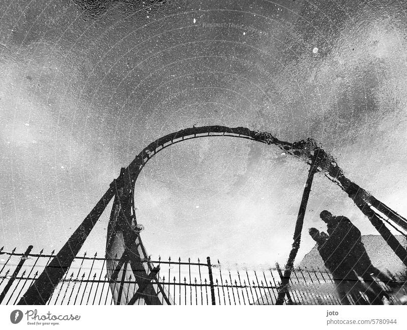 Reflection of a roller coaster and two people in a puddle on a rainy day Umbrella Roller coaster Puddle reflection Reflection in the water rainy weather Autumn