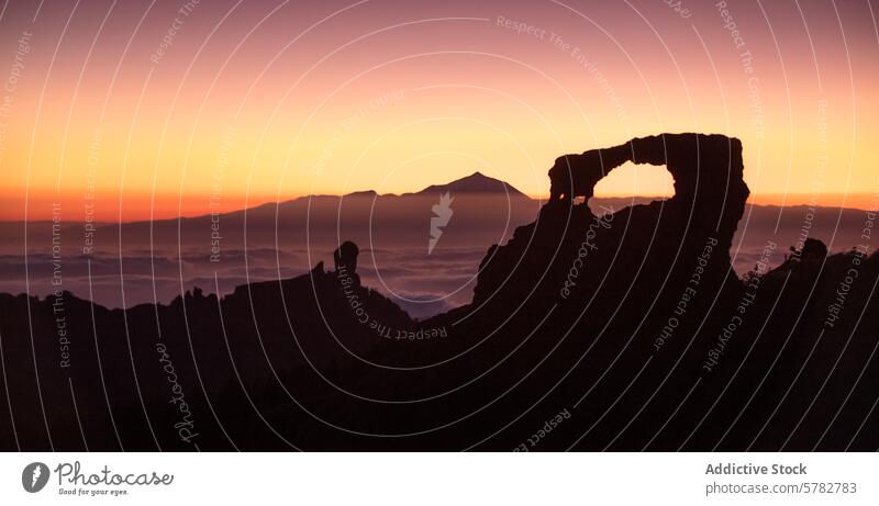 Sunset Through the Arch of Roque Nublo near Teide sunset arch silhouette roque nublo mount teide clouds warm hues framing natural window landmark sea of clouds