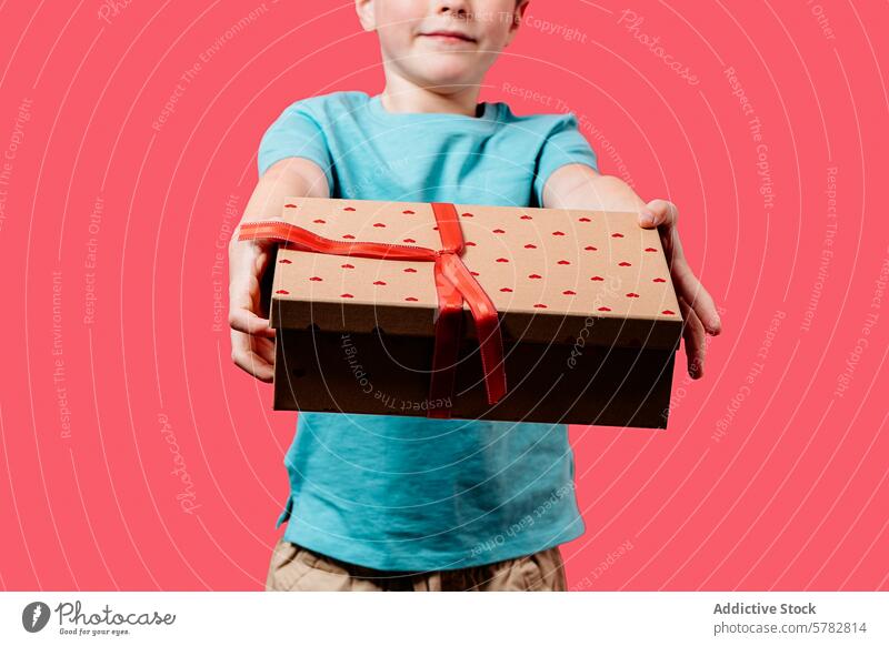 Young boy proudly offering a heart-patterned gift box ribbon giving cheerful present kindness red symbolize child hold celebration generous birthday christmas