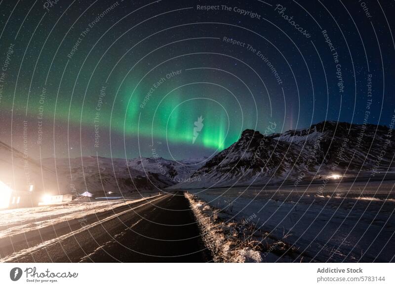 Majestic Northern Lights over snow-covered Iceland road aurora borealis northern lights iceland night mountain landscape green sky natural phenomenon winter