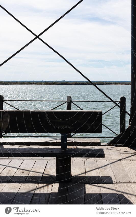Serene waterfront view from Huelva pier with bench huelva sea tranquil metal railing wooden geometric pattern spain coast seaside relaxation perspective travel