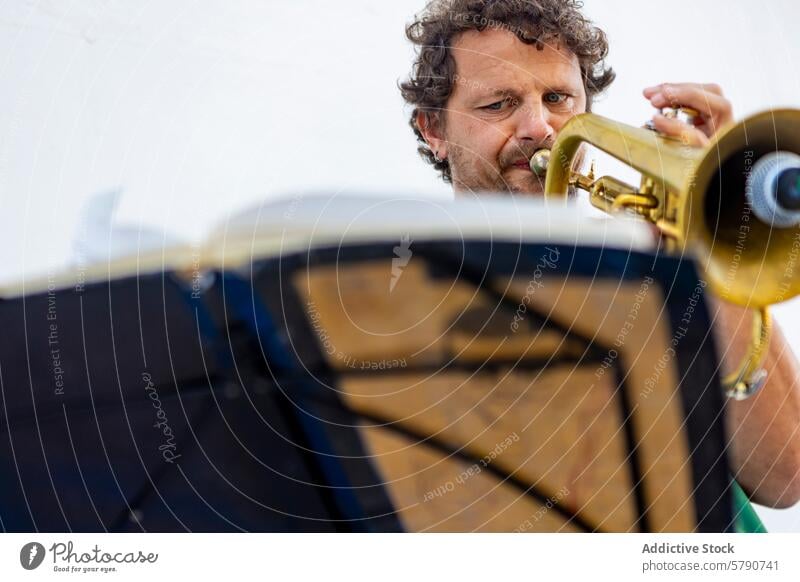 One-armed man playing trumpet with music stand one-armed street performance musician focus skill lens-flare daylight outdoor culture art dedication performer