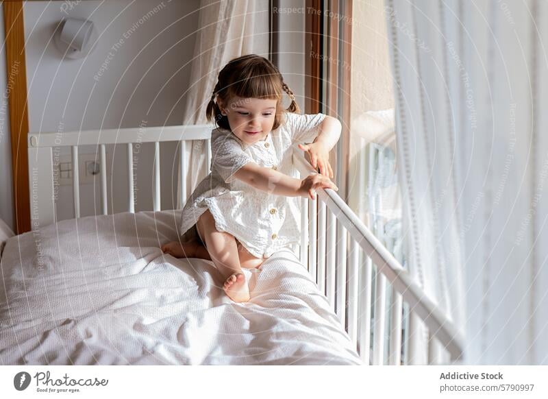 Toddler girl enjoys playtime on a sunlit bed toddler sunny window cozy bedroom cheerful child playing indoors home sunlight morning happy lifestyle nursery
