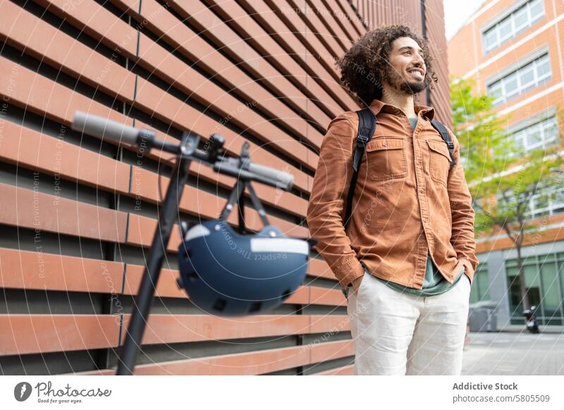 Man with electric scooter enjoying a break in urban setting man lifestyle eco-friendly transportation modern casual thoughtful standing outdoors city helmet