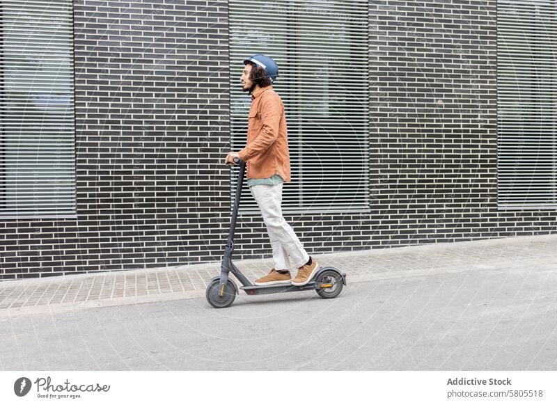 Man in orange jacket riding an electric scooter man urban eco-friendly commute city modern helmet safety vehicle personal transport rider mobility sustainable