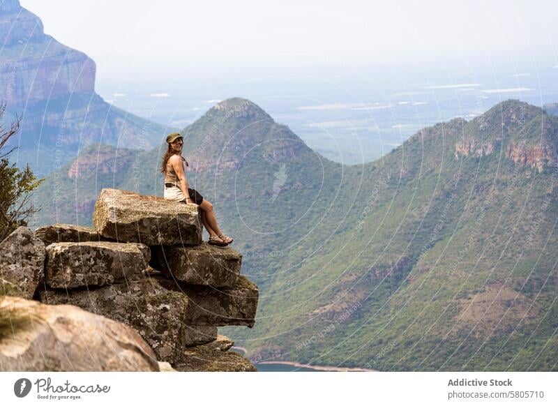 Serene mountain view with female traveler woman sitting rock landscape overlook serene nature outdoors adventure scenic tranquility relaxation Africa tourist