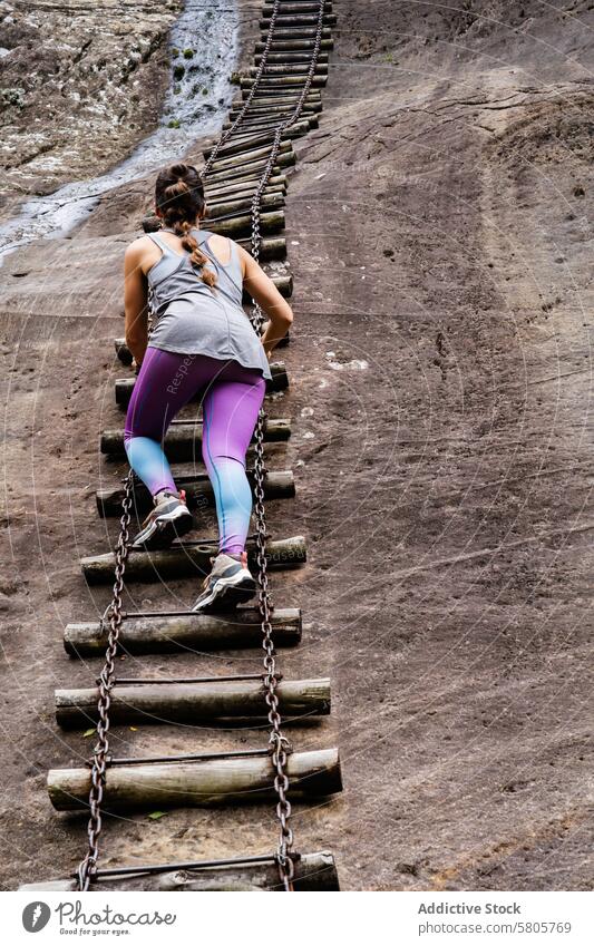 Adventurous Hiker Climbing a Rugged Mountain Ladder hiker female climbing mountain ladder adventure determination steep wooden metal chain outdoor active