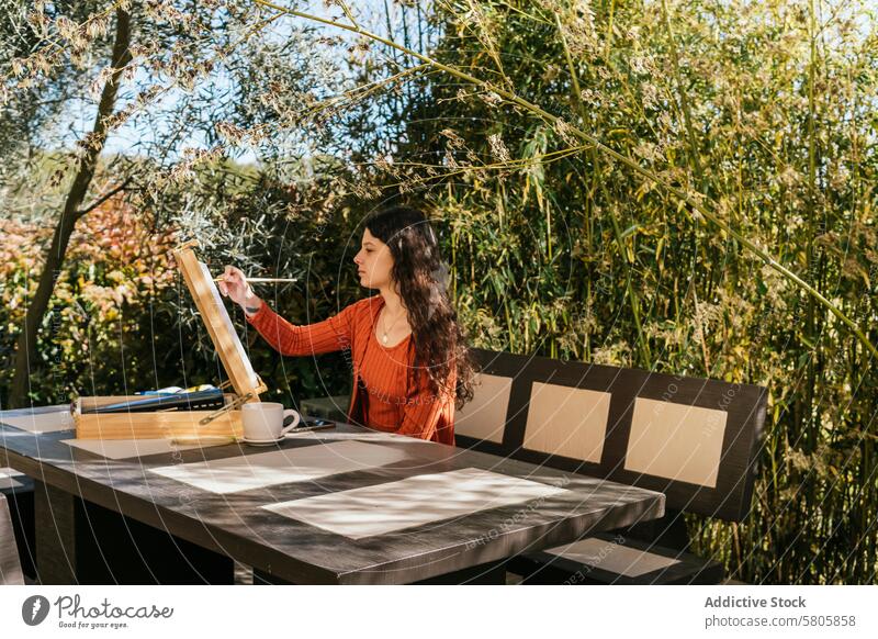 Woman Painting Outdoors on a Sunny Day woman artist painting outdoors canvas greenery sunny creativity brush hobby leisure nature garden tranquil easel painter