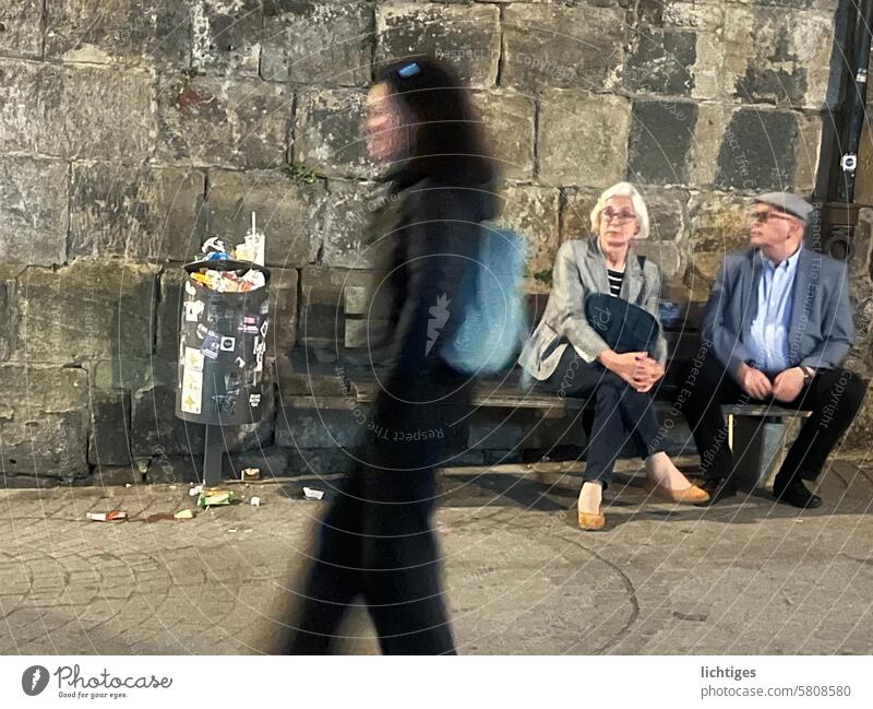 Pre-Byby... - Young woman passes in front of a waiting elderly couple, trash can next to her Passer-by Going Trash Generations Bench dustbin blurred