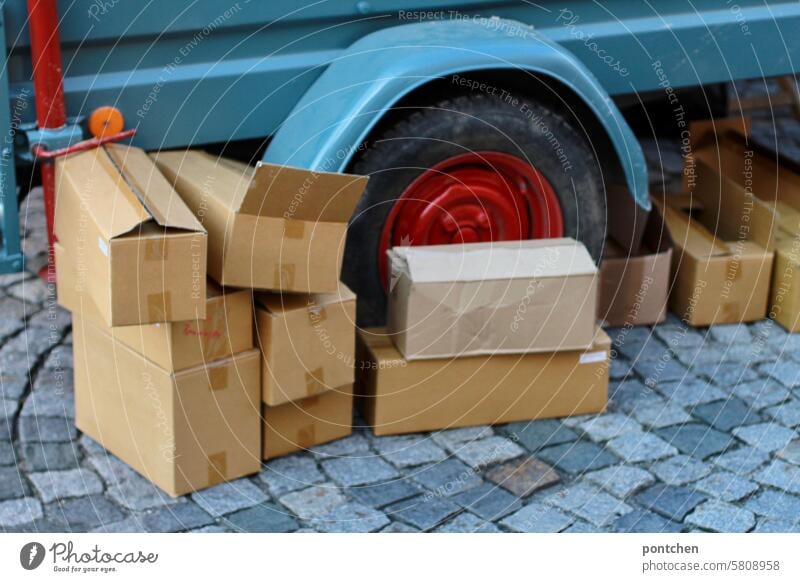 Flea market. Cardboard boxes of various sizes on paving stones in front of a car trailer Transport cardboard boxes safekeeping Car trailer vintage Empty sale