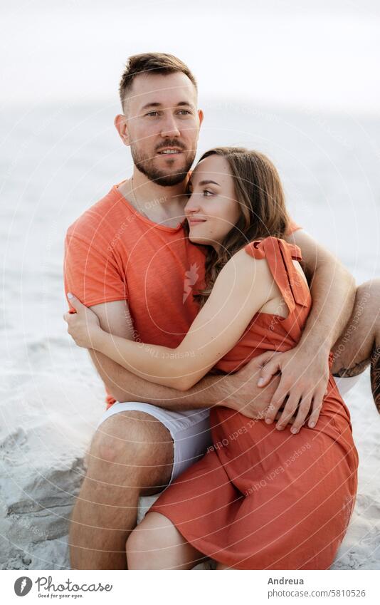 young couple in orange clothes with dog barefoot beach blue coast desert dress empty hot nature outside the house sandy shorts summer together walk white