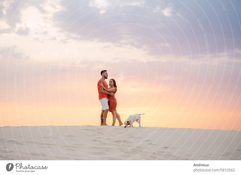 young couple in orange clothes with dog barefoot beach blue coast desert dress empty hot nature outside the house sandy shorts summer together walk white