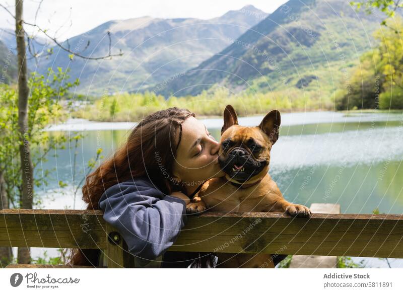 Female traveler kissing dog near lake in mountains woman french bulldog friend together female pyrenees nature cute happy adorable domestic companion cheerful