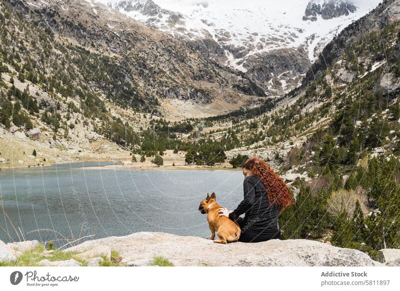 Traveling woman with dog in mountains traveler lake viewpoint pet highland pond pyrenees female together admire canine stone animal rock french bulldog nature