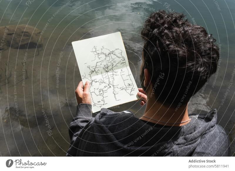 Traveling man reading map near lake in highlands traveler navigate orientate mountain search male pyrenees trip route journey explore direction vacation