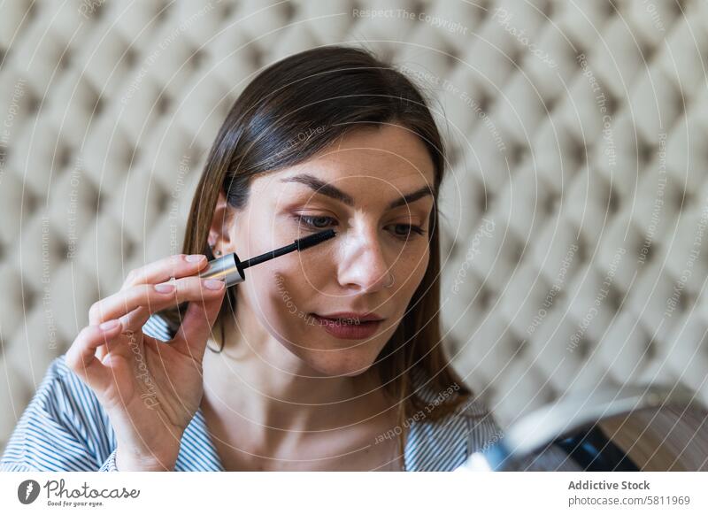 Beautiful woman applying mascara on eyelashes makeup mirror cosmetic focus beauty visage pamper brush routine daily style prepare care attractive brunette young