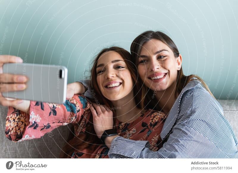 Smiling women hugging and taking selfie on smartphone toothy smile friend happy together embrace self portrait young cheerful girlfriend positive casual