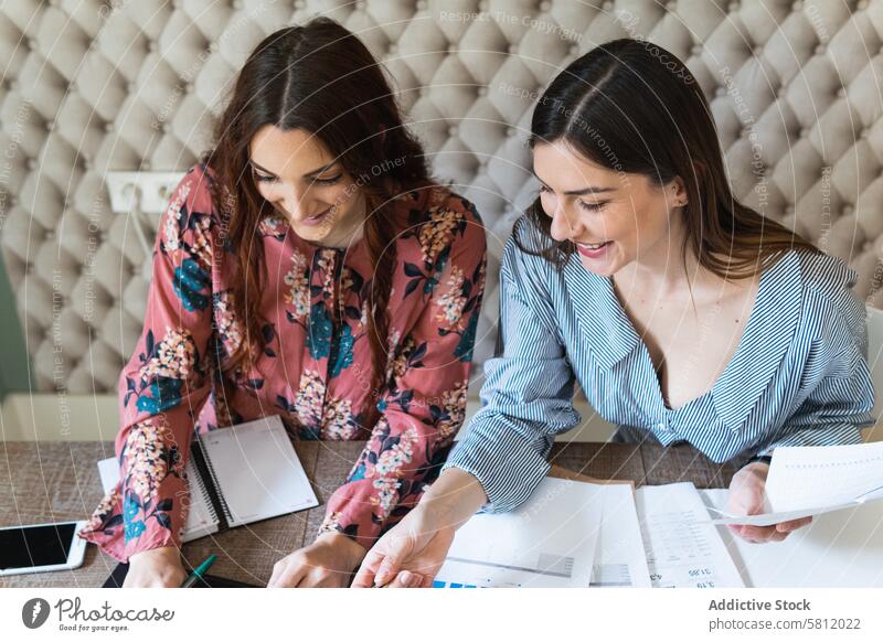 Crop focused female colleagues analyzing charts together in office women analyze work paperwork laptop workplace diagram workspace teamwork coworker