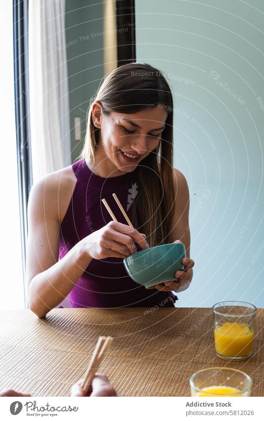 Cheerful woman with chopsticks having lunch in dining room eat food happy toothy smile delicious enjoy meal asian food hungry appetite lifestyle content