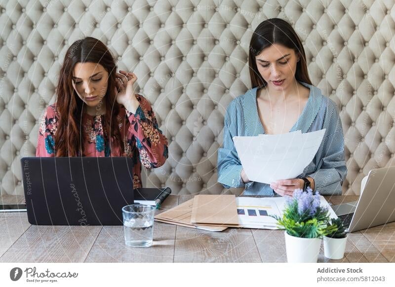 Focused women working on laptops in coworking space paperwork office workplace colleague busy workspace teamwork coworker professional browsing gadget device