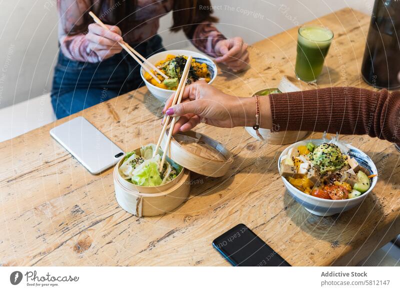 Crop woman eating poke dish in restaurant serve tasty tradition hawaiian food delicious female meal chopstick portion bowl hawaiian cuisine yummy table wooden