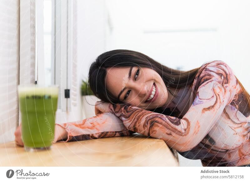 Content woman enjoying green beverage in bar chill weekend counter content cheerful relax smile female modern glad young positive lean on hand happy rest