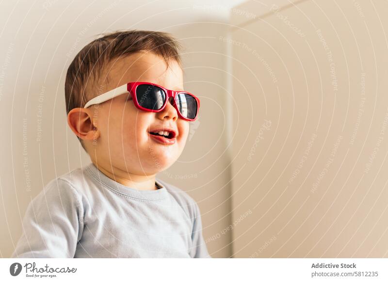 funny baby with sunglasses sitting at home cute happy child kid young caucasian toddler little background portrait girl people fashion indoors family white