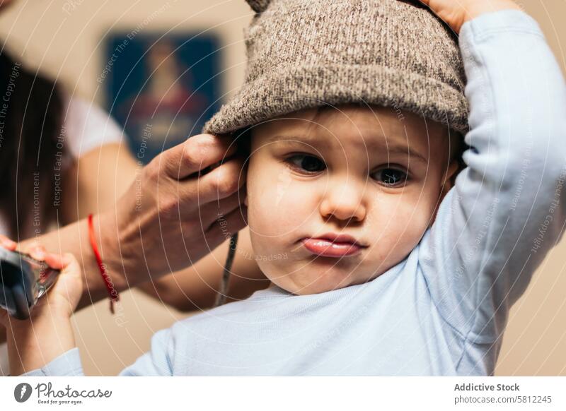 mother putting a hat on her baby at home woman child childhood love kid family parent smile young happy happiness caucasian beautiful female lifestyle fun mom