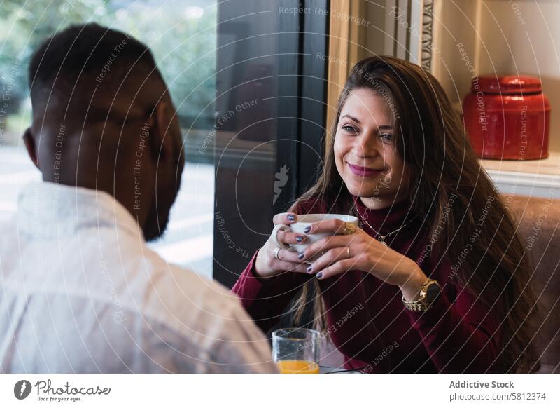 Multiracial couple chatting during breakfast in cafe together drink happy morning cup relationship love communicate cozy beverage cheerful lifestyle rest mug