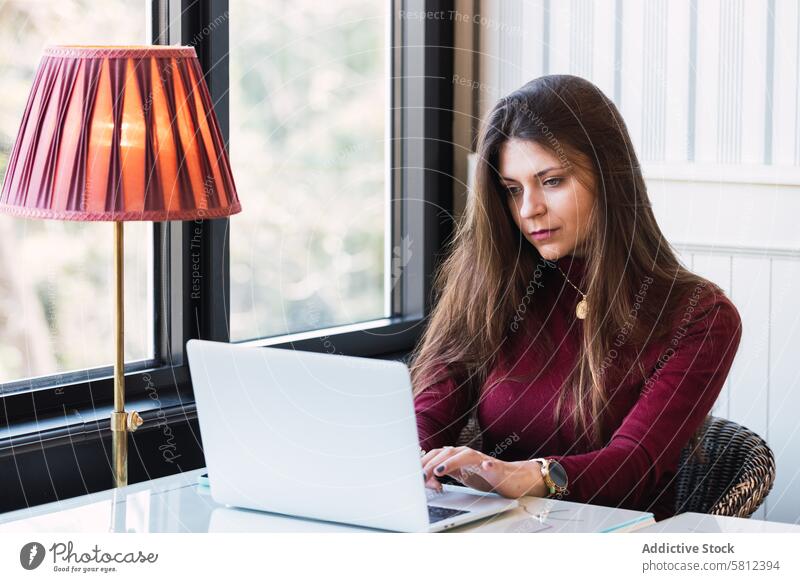 Woman working on laptop in cafe woman using remote freelance online telework digital modern female serious young gadget browsing device internet job lifestyle