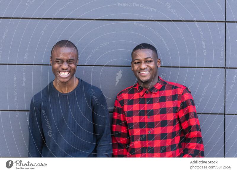 Happy black male friends against gray wall men personality happy smile gaze confident individuality youth appearance stare charismatic friendship casual ethnic