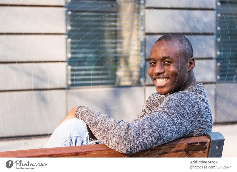 Cheerful black man resting on urban bench spare time weekend cheerful friendly enjoy street town african american toothy smile glad ethnic positive pleasant