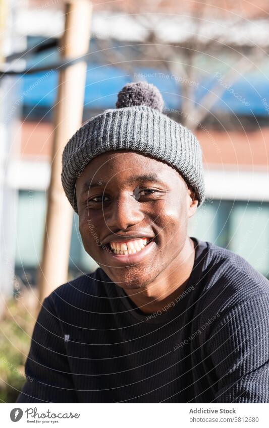 Smiling black man in hat in sunny park smile portrait positive joy carefree enjoy human face appearance stare male toothy smile sunlight happy sincere delight