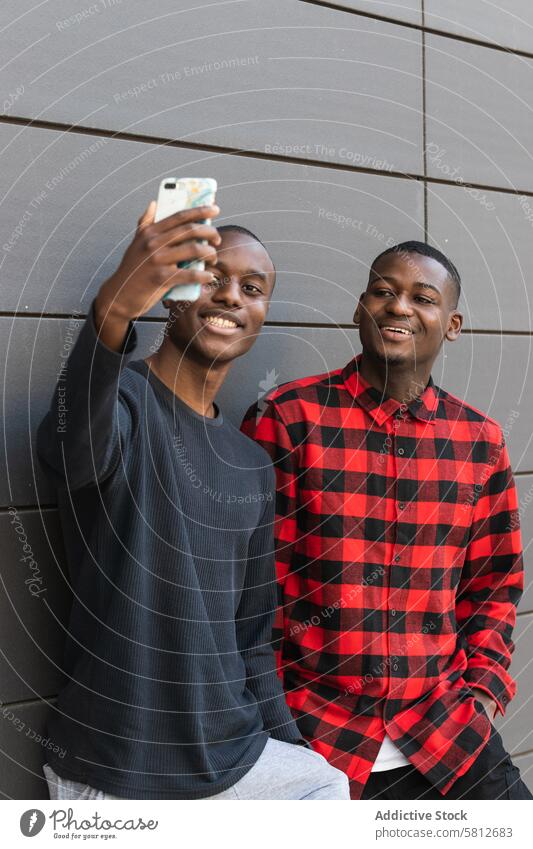 Black smiling men taking selfie on smartphone using friend together cheerful glad positive friendship male happy cellphone toothy smile joy casual device