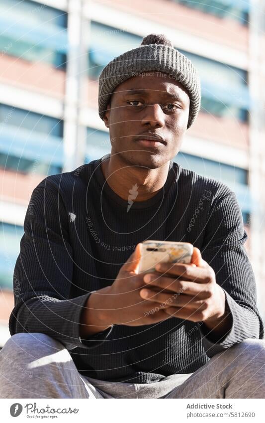 Serious black man using smartphone sitting on street serious focus browsing connection think internet digital male online young cellphone device surfing mobile