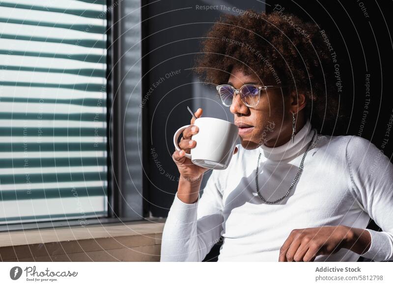 Pensive young ethnic man drinking coffee and looking away in cafe relax pensive coffee break chill style enjoy confident trendy male african american man