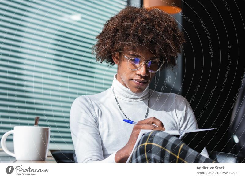 Concentrated trendy young black guy doing assignment in cafe man take note exam preparation confident style smart fashion coffee education serious concentrate