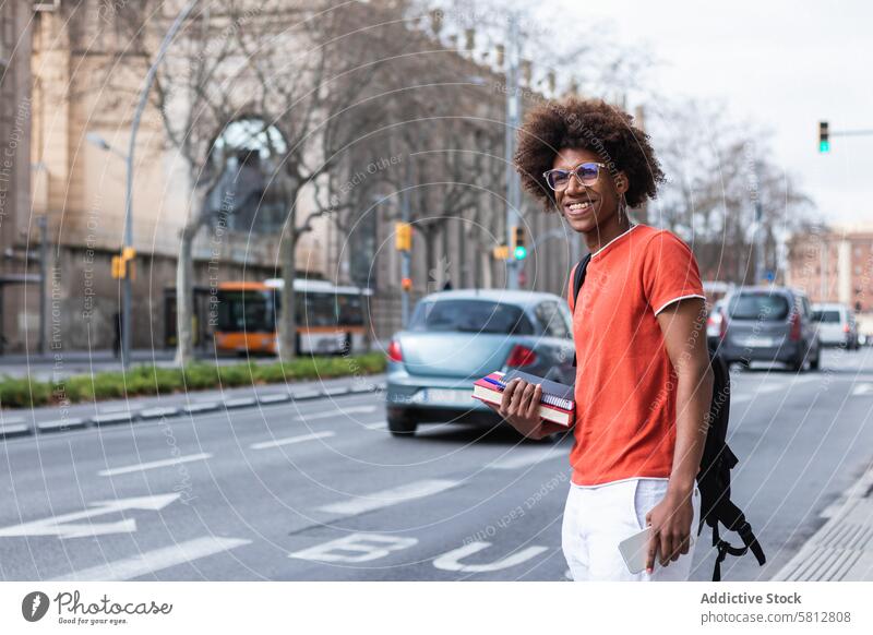 Smiling young black male student standing at bus stop in city man wait smile style street urban cool education serious content confident african american man