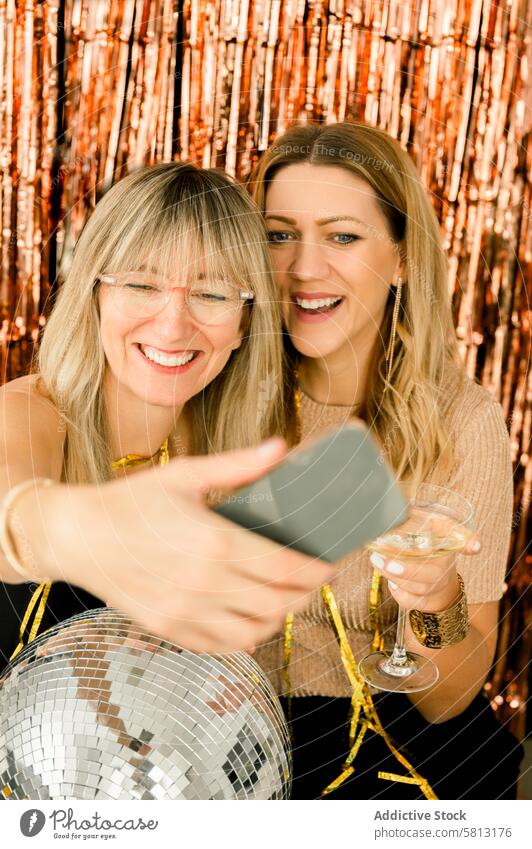 Cheerful girlfriends taking selfie in evening dress on party woman smartphone laugh night elegant smile joy cheerful celebrate event happy tinsel holiday style