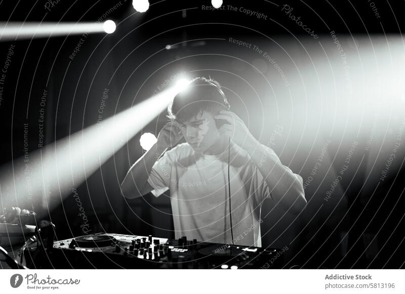 Unsaturated photo of a disc jockey at turntables black and white unsaturated dj people man young caucasian stage touch young adult headset nightclub electronic