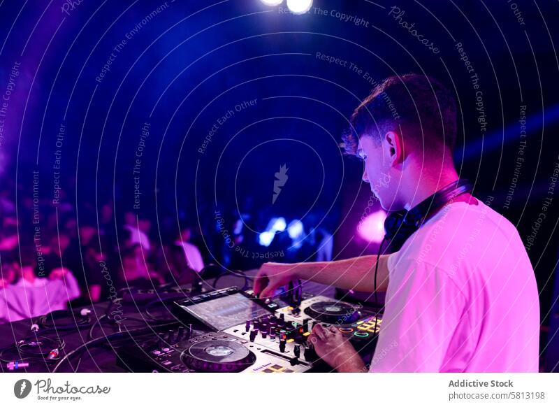Rear side view of a dj working on a discotheque rear view copy space man young casual caucasian concert perform mix party technology nightclub neon indoors
