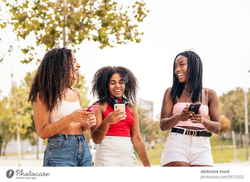 African American Friends Enjoying Summer Together and using smartphone Smartphone Diversity Youth Connection Communication Joy Laughter Happiness Leisure