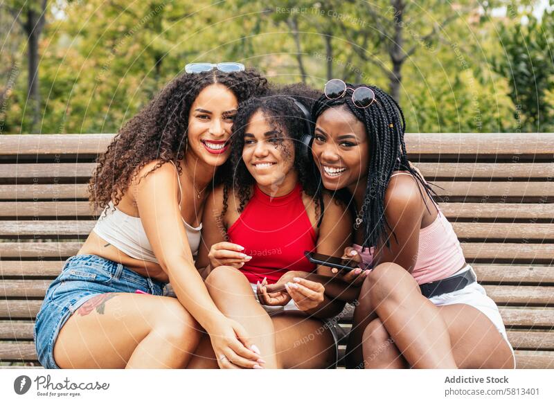 African American Friends Enjoying Summer Together and using smartphone Diversity Youth Communication Joy Laughter Happiness Leisure Relaxation Outdoors Fun