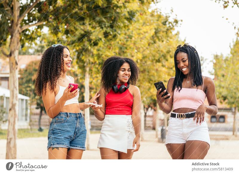 African American Friends Enjoying Summer Together and using smartphone Diversity Youth Communication Joy Laughter Happiness Leisure Relaxation Outdoors Fun