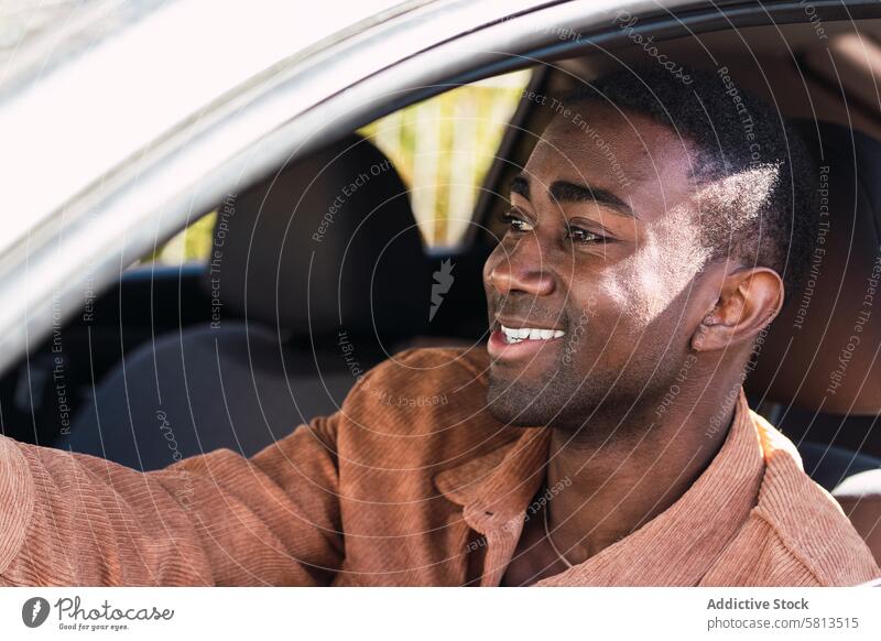 Cheerful black man in car driver automobile smile commute appearance window street steering wheel positive african american transport modern city trendy glad