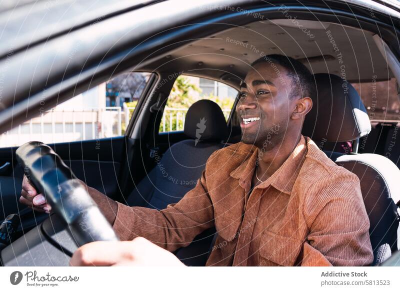 Cheerful black man in car driver automobile smile commute appearance window street steering wheel positive african american transport modern city trendy glad