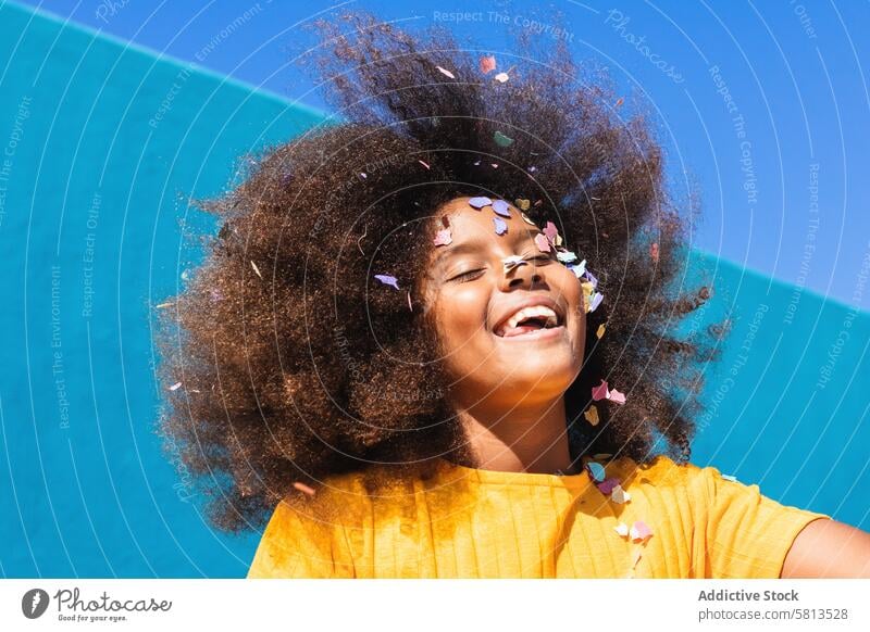 Delighted black girl having fun with confetti kid happy colorful curly hair afro carefree summer sunny teen african american ethnic female cheerful joy optimist