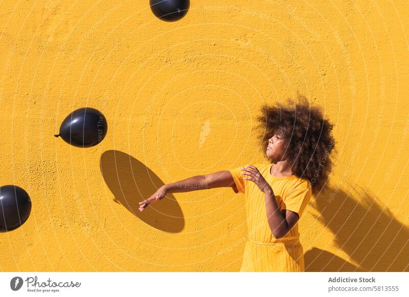 Happy black girl playing with balloons yellow afro curly hair colorful having fun vivid child kid teenage hairstyle ethnic african american happy sunlight